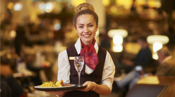 Service employee at Virgin Atlantic Clubhouse smiling while holding a tray